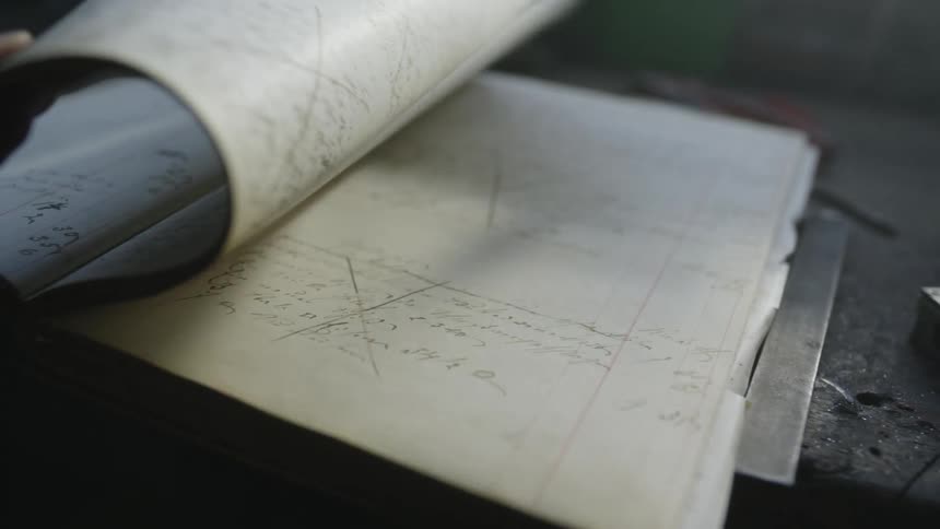 A person slowly turns the pages on a notebook that is filled with handwriting