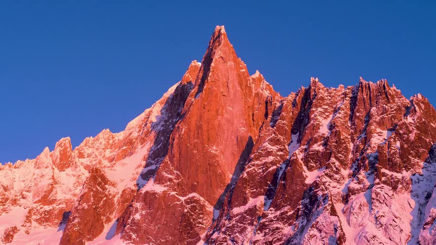 A mountain with a sky behind it shows the full moon rising and setting in a time lapse effect