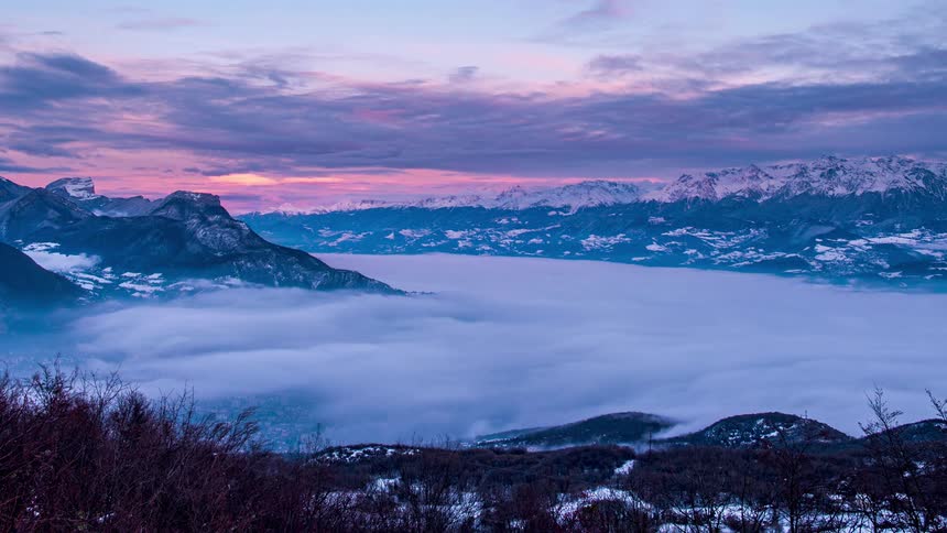 Fog fills valley on winter day as red sky fades during dusk