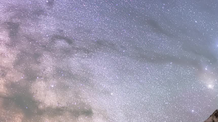 A time lapse of a snowy mountain ridge revealing a starry night sky