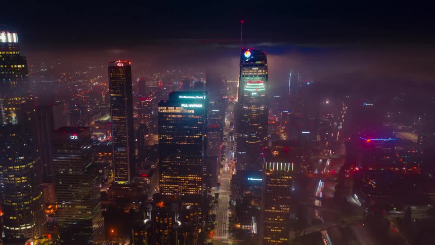 An aerial view of a metropolis at night with neon signs and lights on skyscrapers