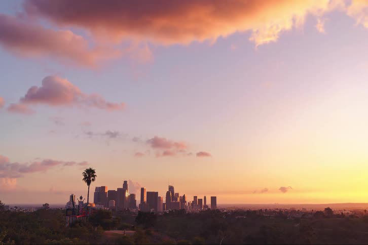 Time lapse of clouds shifting colors while rolling over the city skyline at evening