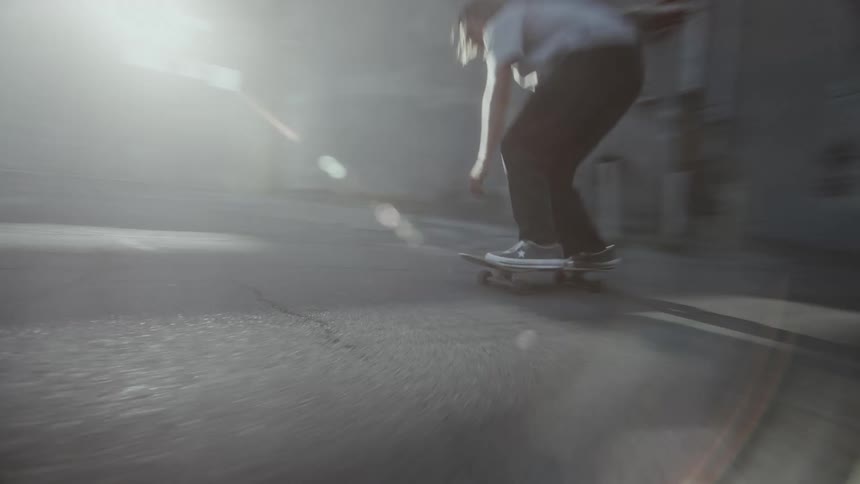 Three teenagers riding skateboards through an alley with buildings on either side