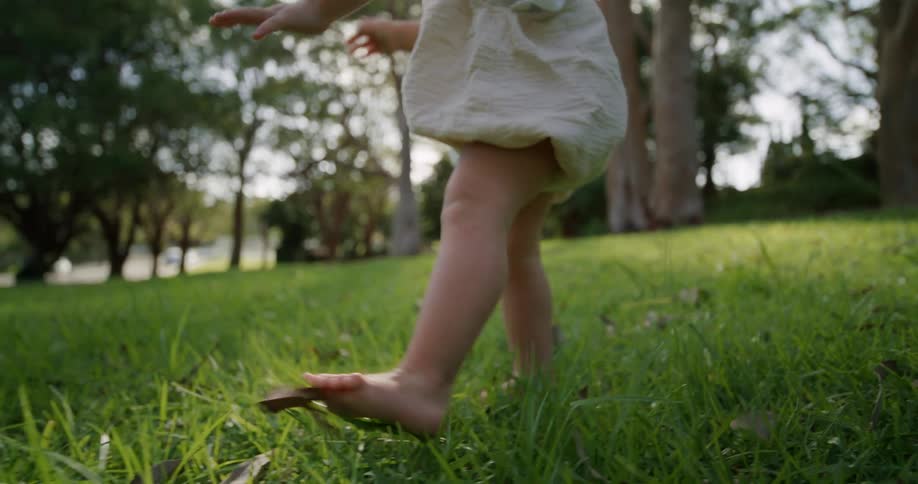 The view is of a toddler that is walking outdoors in the day time