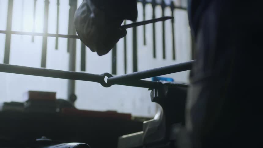 A metal worker in a factory workshop inserts a metal pipe into the hole on a machine