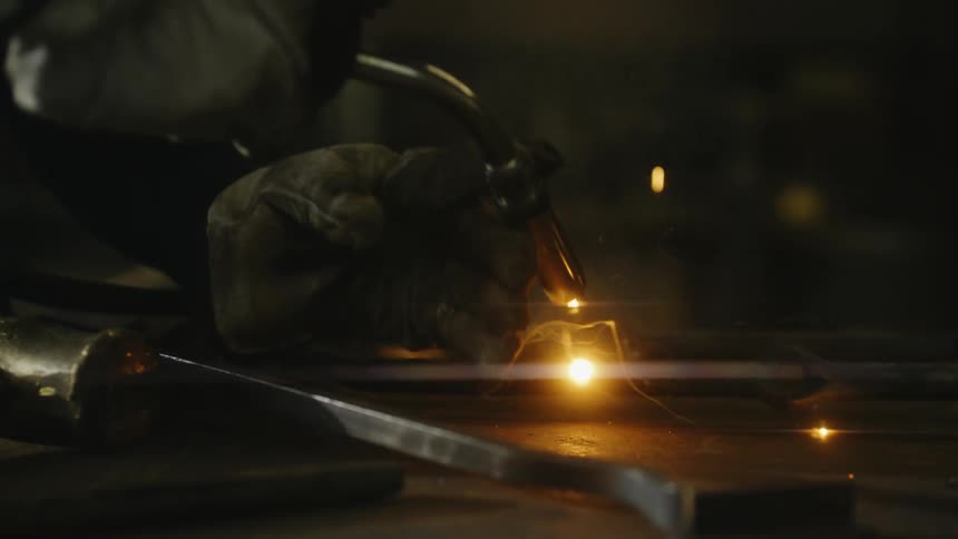 A man uses a torch on a metal rod