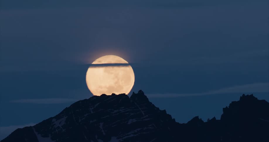 Time lapse of the full moon setting behind the mountains at night