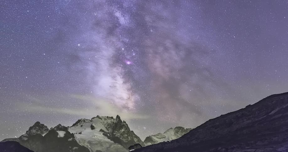 A still time lapse shot of the starry night sky behind a mountain peak