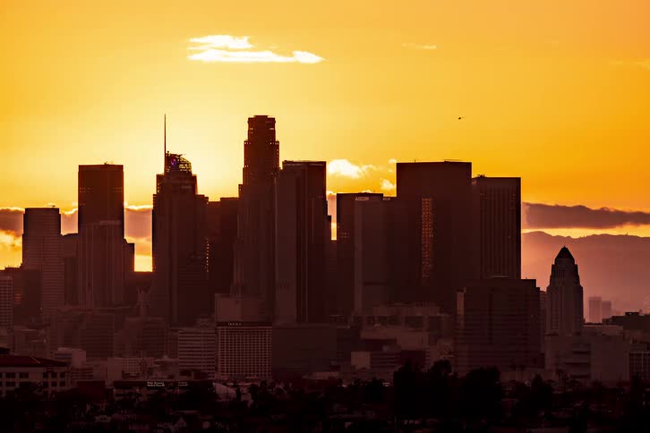 A time lapse of the silhouette of a city with tall buildings as the night sky starts to settle in