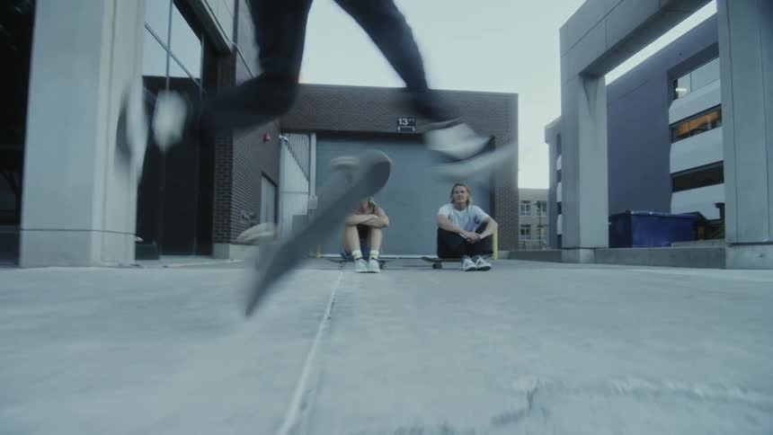 Skateboarder with white t-shirt and black pants does tricks with skateboard
