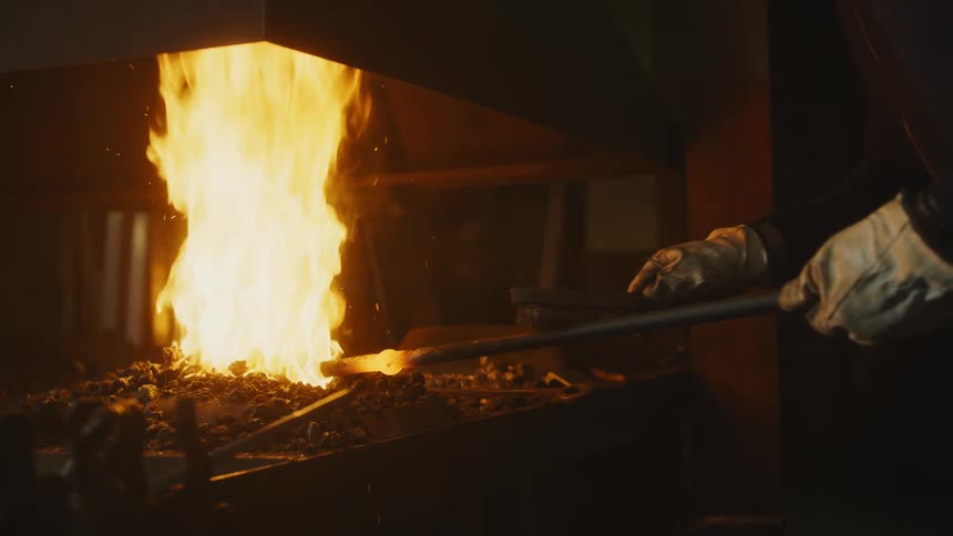 A blacksmith is brushing hot metal
