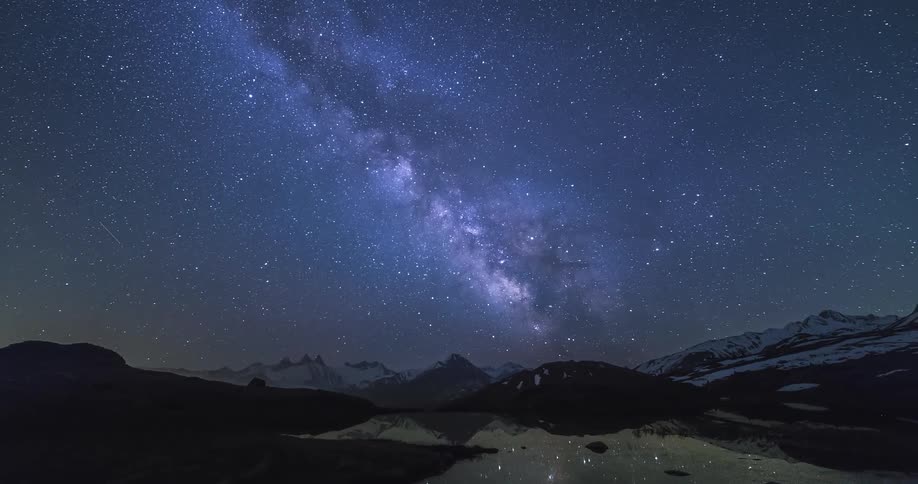 A starry night sky above a snowy mountain range in nature