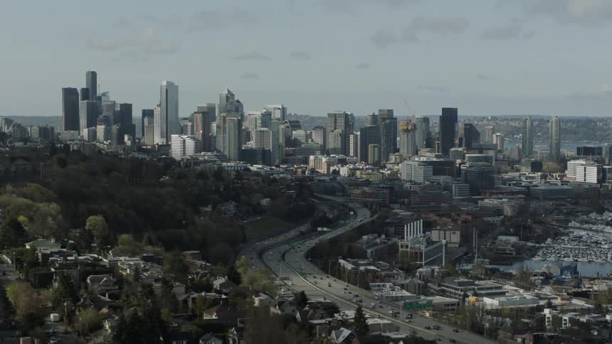 Cars drive on a city road with skyscrapers in the distance