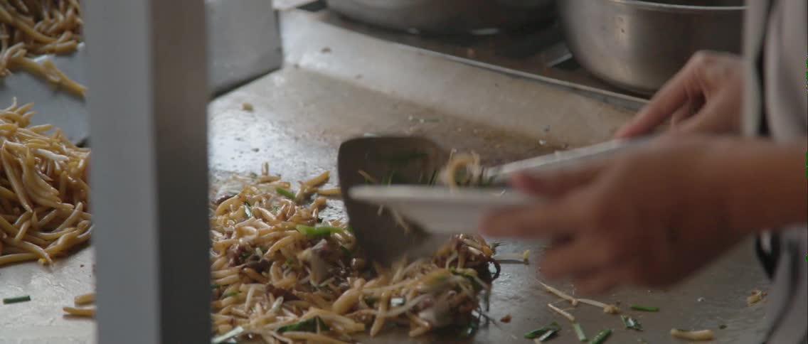 A person cooks food on a stove spooning it around