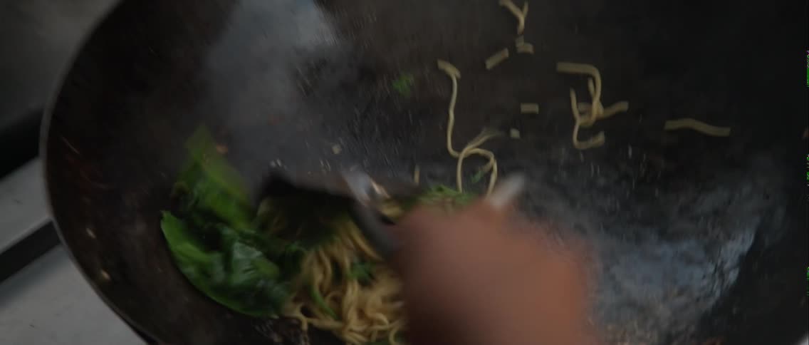 A person is cooking some food in a wok