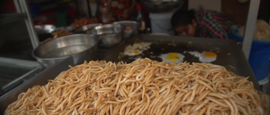 A large pile of food in front of a flat top grill