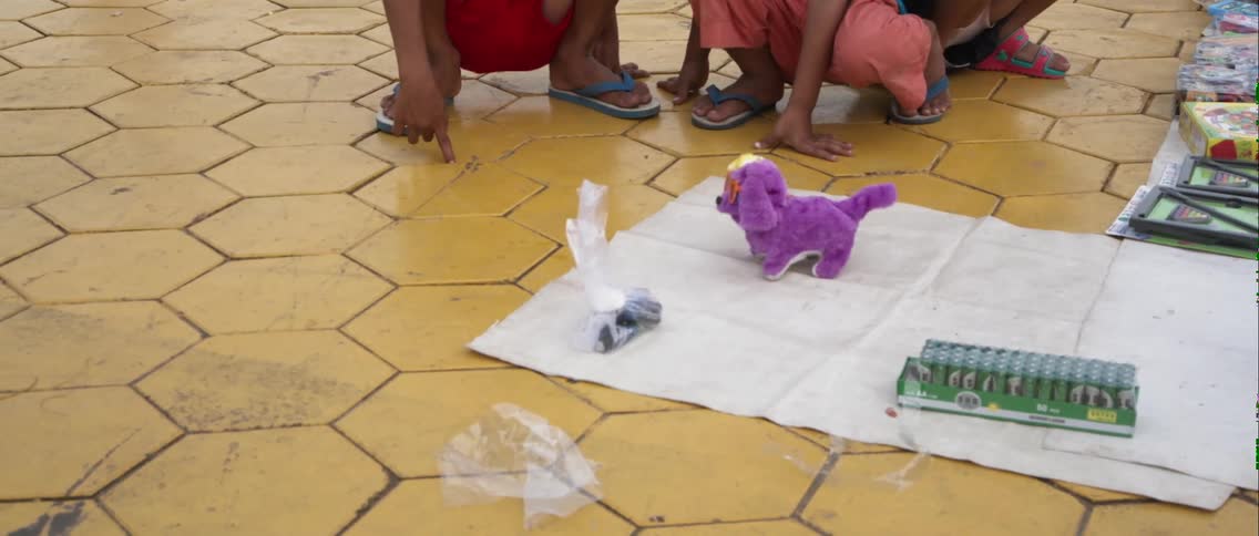 Children watch a toy dog walk on a mat