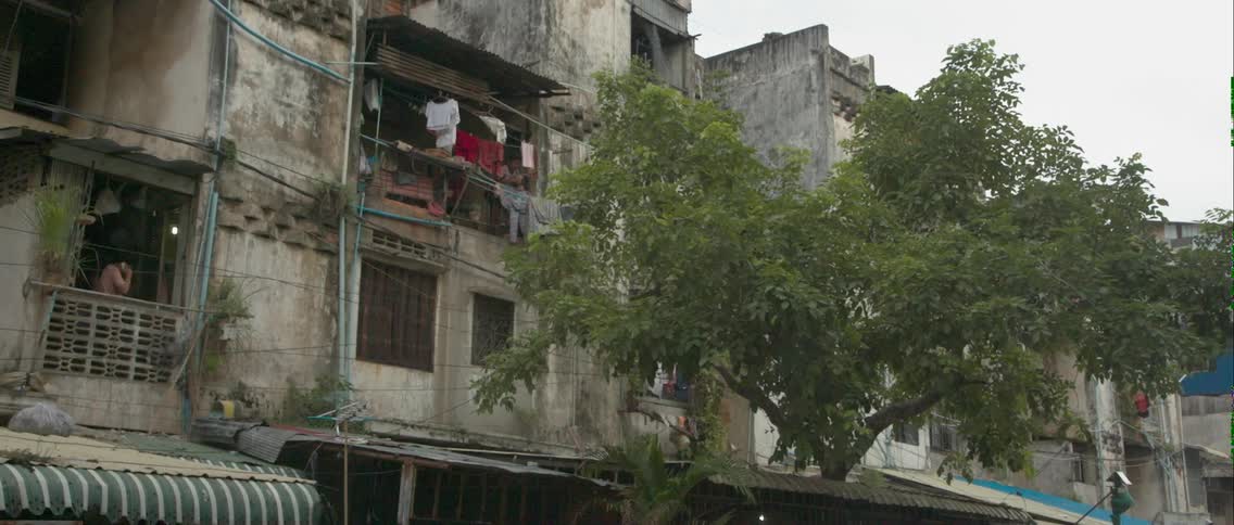 Clothes hanging on a line on a second story balcony of an abandoned looking building