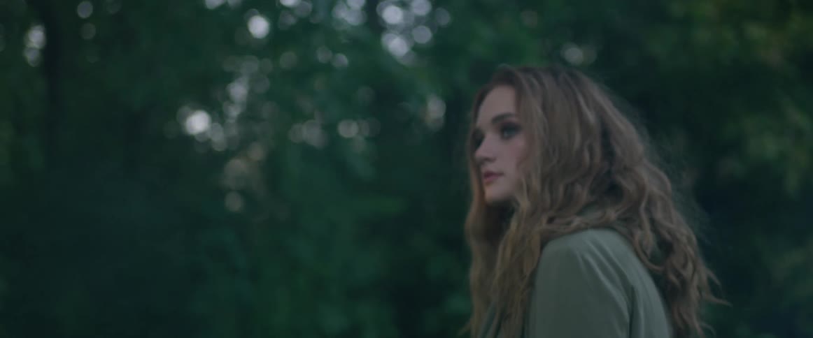 A woman walks past trees looking to the side