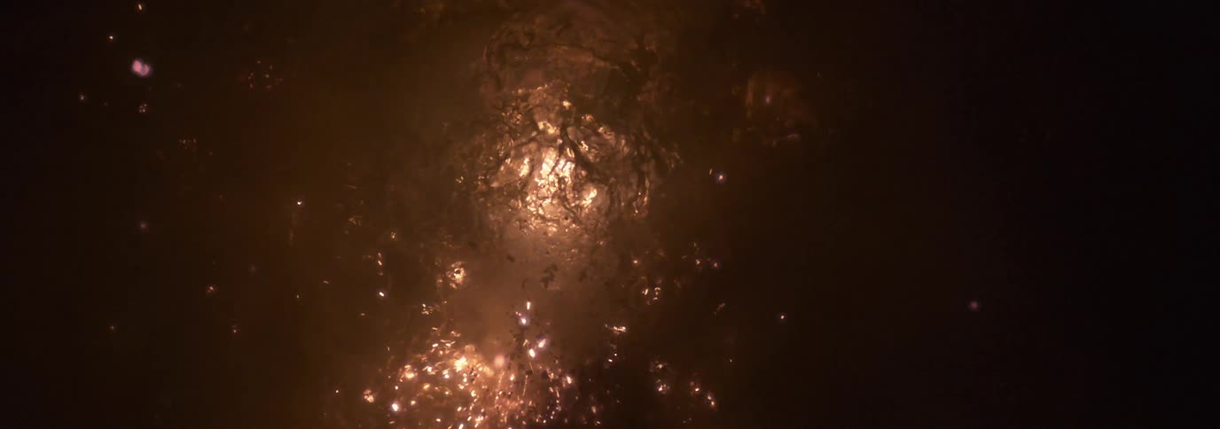 Sparks fly from an explosion underwater in the dark