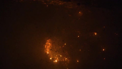 Smoke rises from the fire at night as sparks rise from the flames