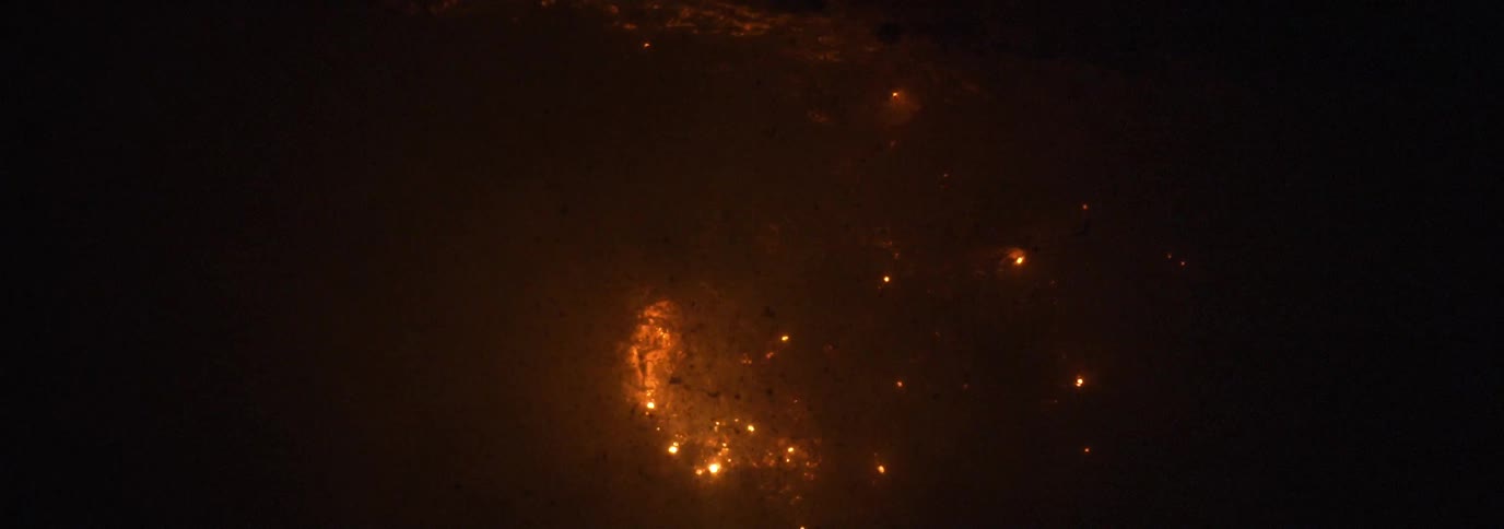 Smoke rises from the fire at night as sparks rise from the flames