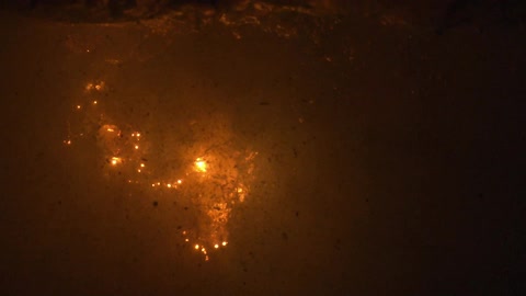 Orange and yellow fireworks explode in the night sky