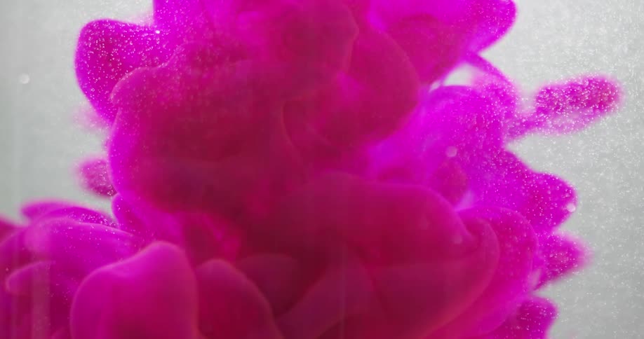 A colorful cloud of liquid pours into a vat of clear liquid
