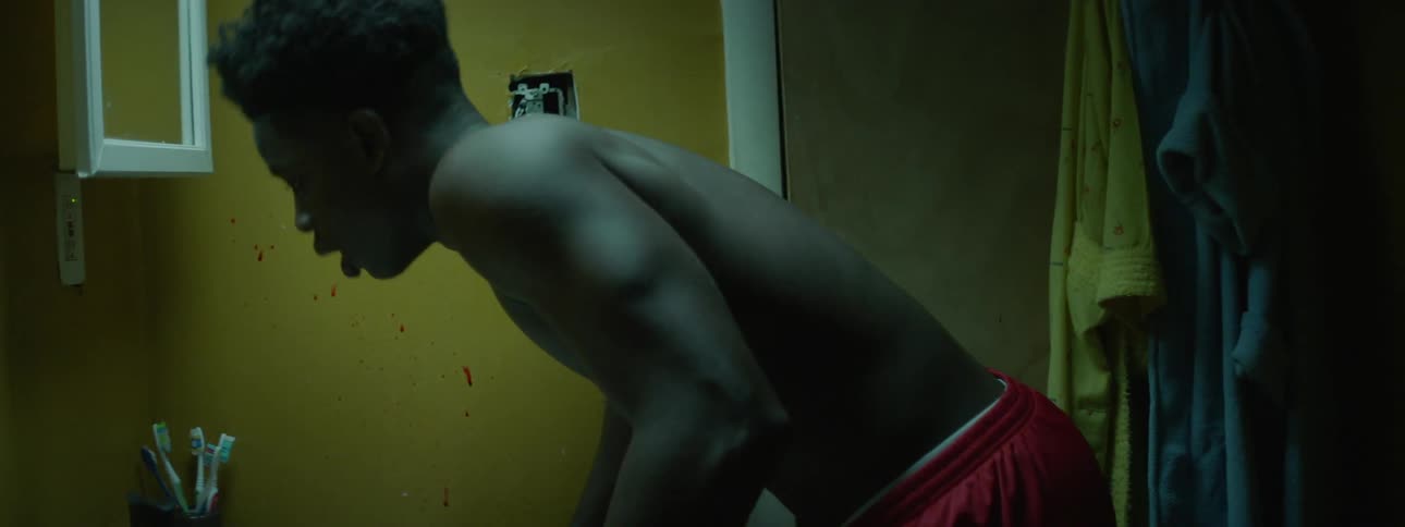 A boy is crouched before a door that is being banged on