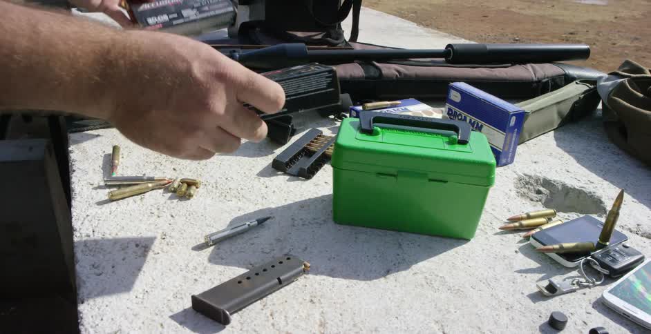 Man organizes bullets and other equipment on a cinder block outside