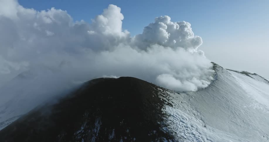 Aerial view of a mountain covered in clouds is displayed