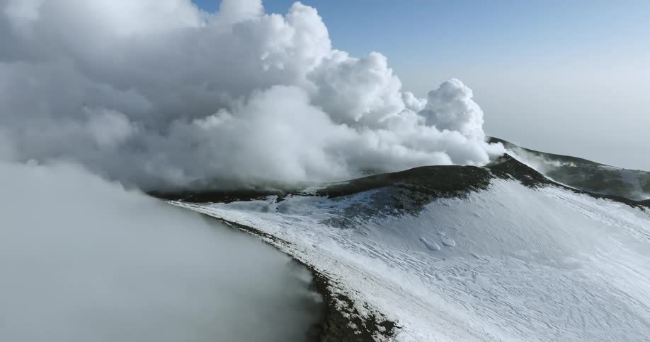 White smoke clouds rise from snow covered volcano