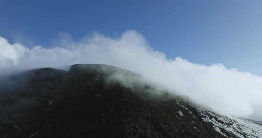 Fluffy clouds move over the peak of a mountain