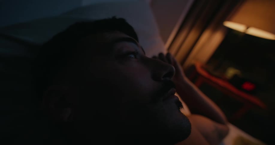 A male is resting in his bedroom during the night time