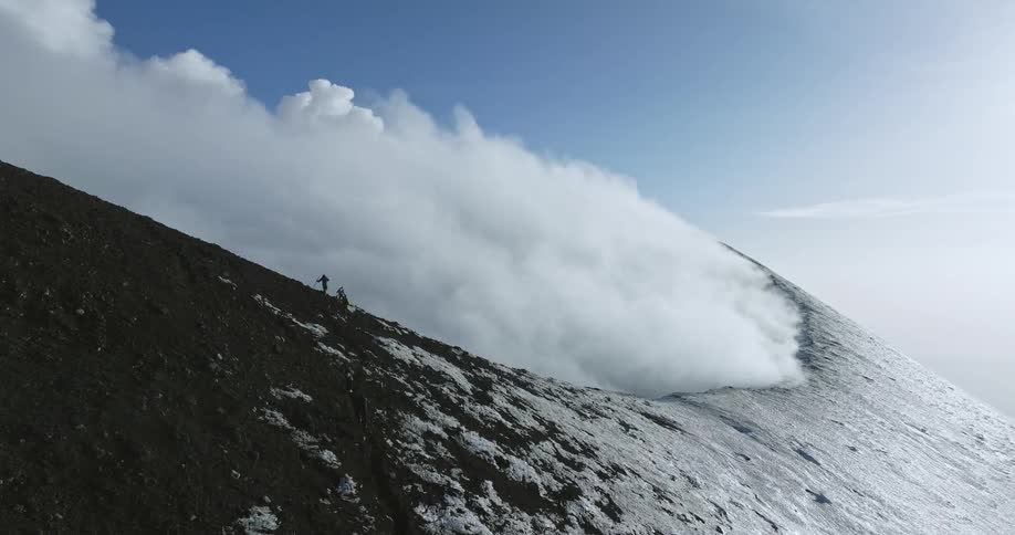 Aerial view orbiting crater of active steamproducing volcano with trekkers on the crater edge