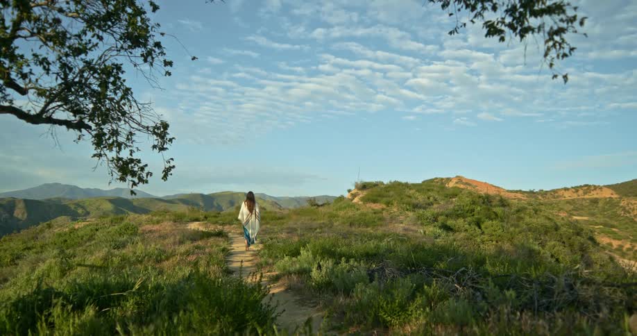 Young native american woman walking along path on wide california landscape