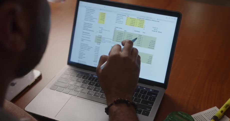 A man reviews numbers in a spreadsheet on his laptop computer screen