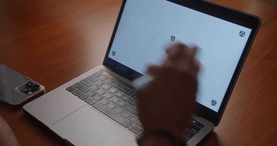 Man with glasses and beaded bracelet uses laptop