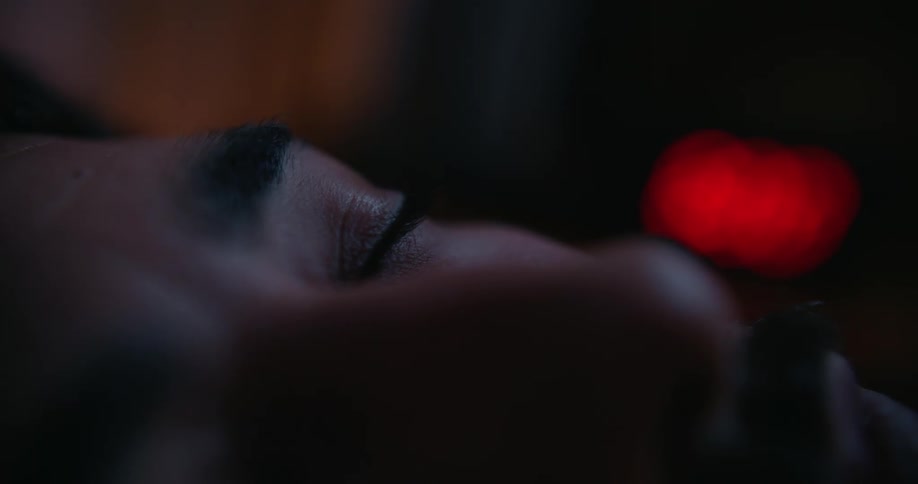 A man opens his eye in a dark room and blinks a few times