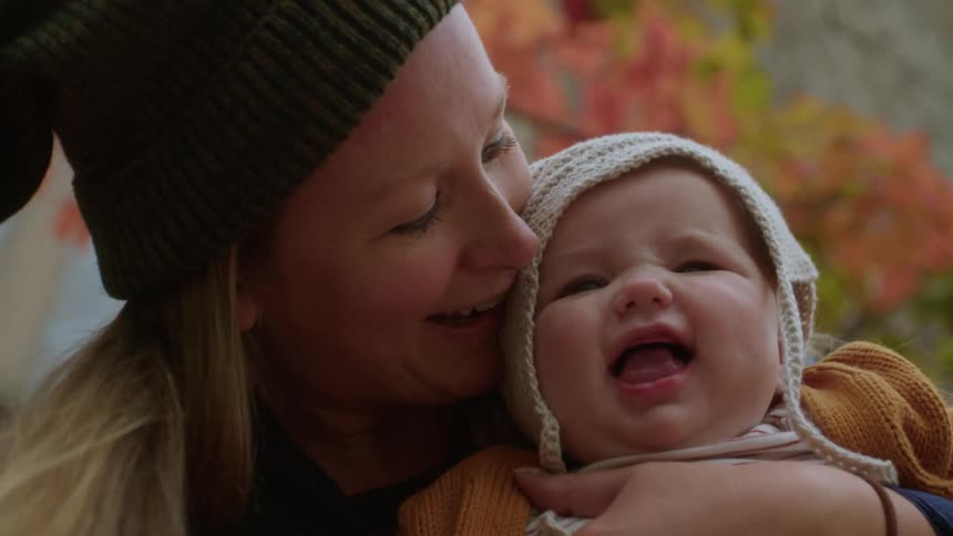 A mother holding and playing with her baby