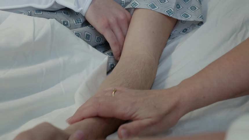 A close up of a boys arm as his mother rubs her hand up and down it