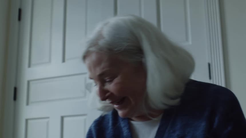 Older woman sits in room near door and smiles while talking and interacting