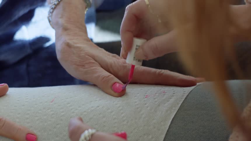 Woman applies fingernail polish to nails of an elderly woman
