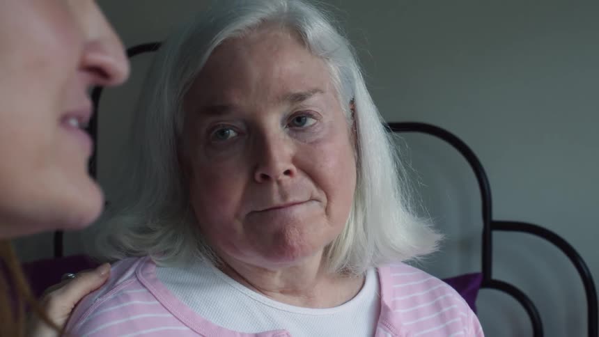 Young woman having a conversation with grandmother while sitting on the bed