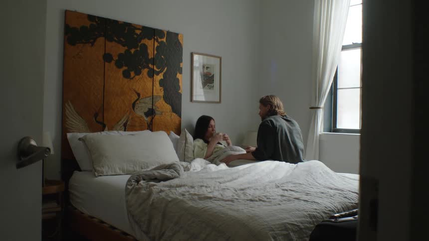 A husband serves his wife a warm drink while she lays in bed sick