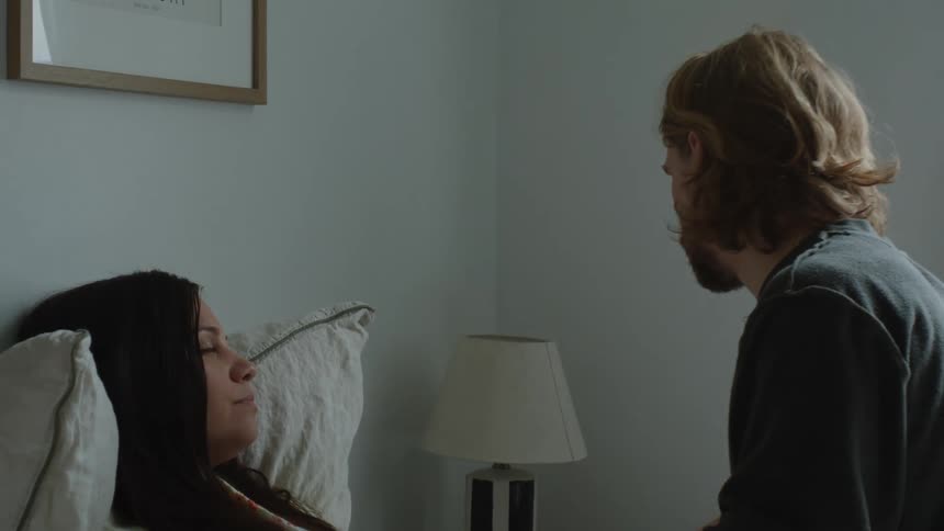 Husbands takes the temperature of his sick wife while she rests on bed
