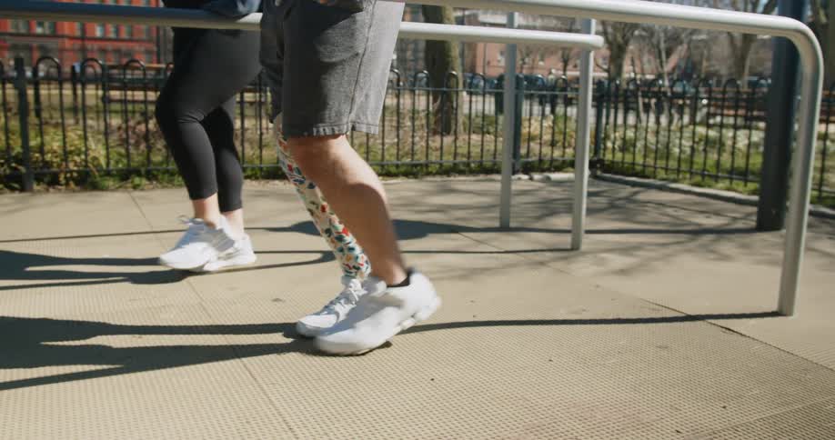 A man with a prosthetic leg practices walking while holding a metal handrail