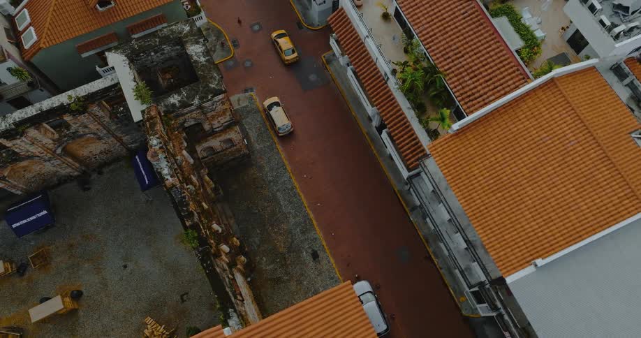 Orbiting around smallish european-style latin american neighborhood with cars going down street and terra cotta roofs