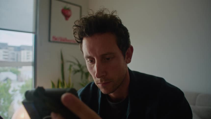 Man sitting on couch looks at camera before typing on laptop