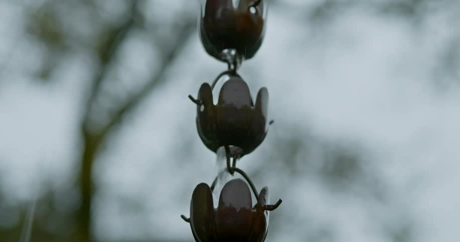 Rain water dripping down a metal ornament hanging outdoors